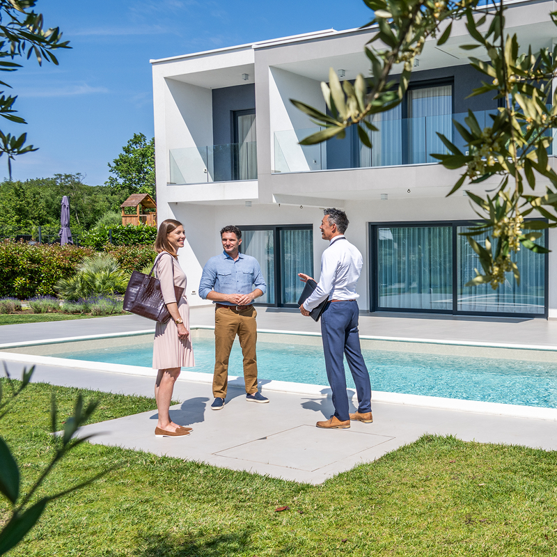People discussing outside modern house with pool.