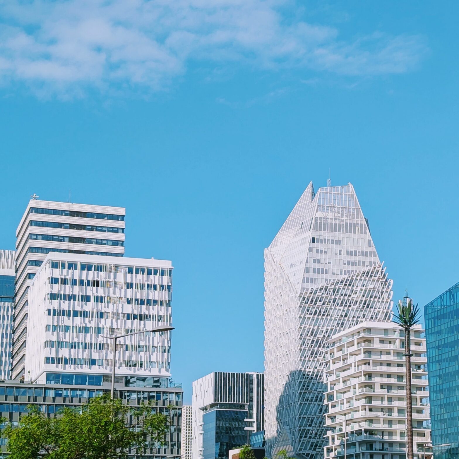 A wide-angle daytime view of the Casa Finance City district in Casablanca, Morocco, showcasing a cluster of contemporary high-rise buildings with unique architectural designs under a clear blue sky